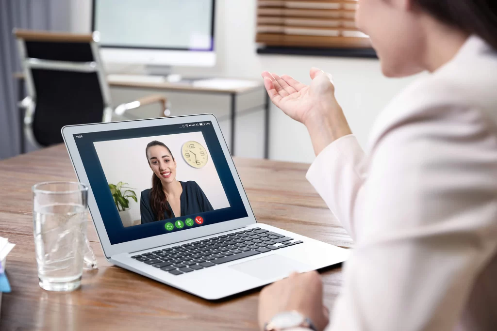 A woman facing a laptop with a video call open, speaking to another woman