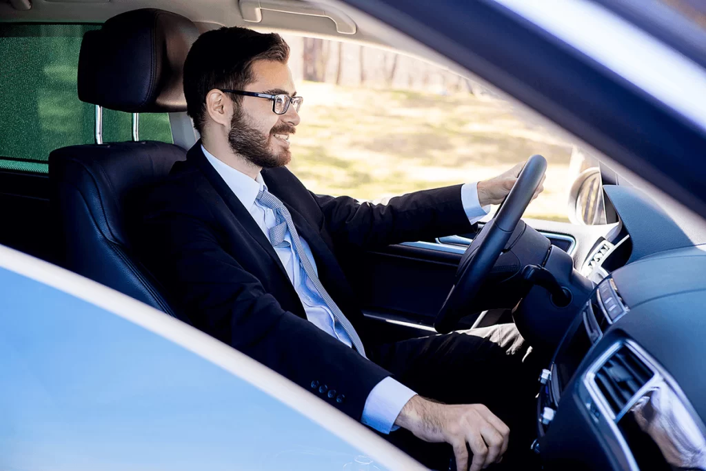 A professionally dressed man driving a car