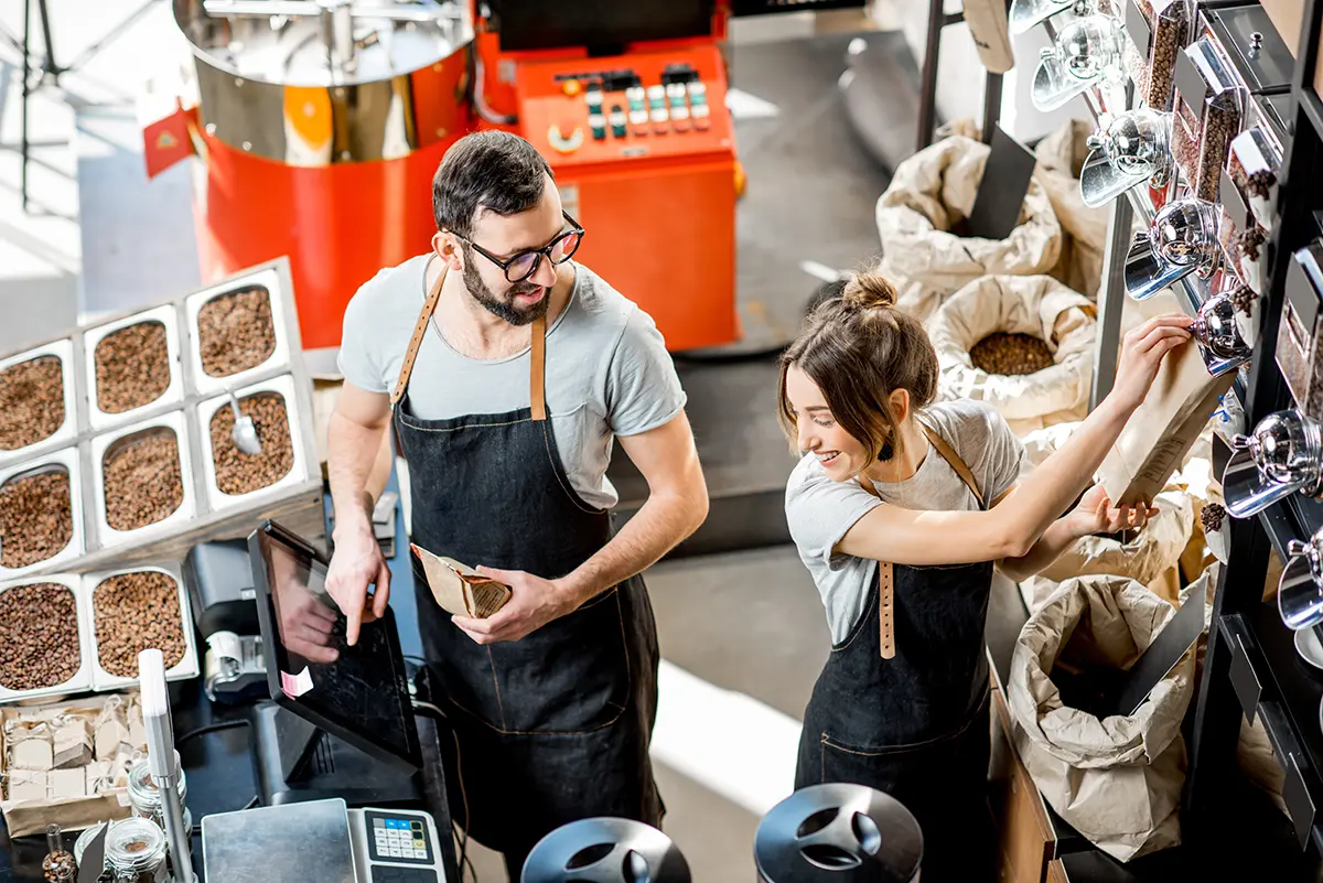 Two people at a coffee roaster working and using a tablet