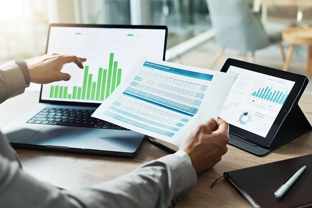 Accountant examining business records on paper, a tablet, and a laptop