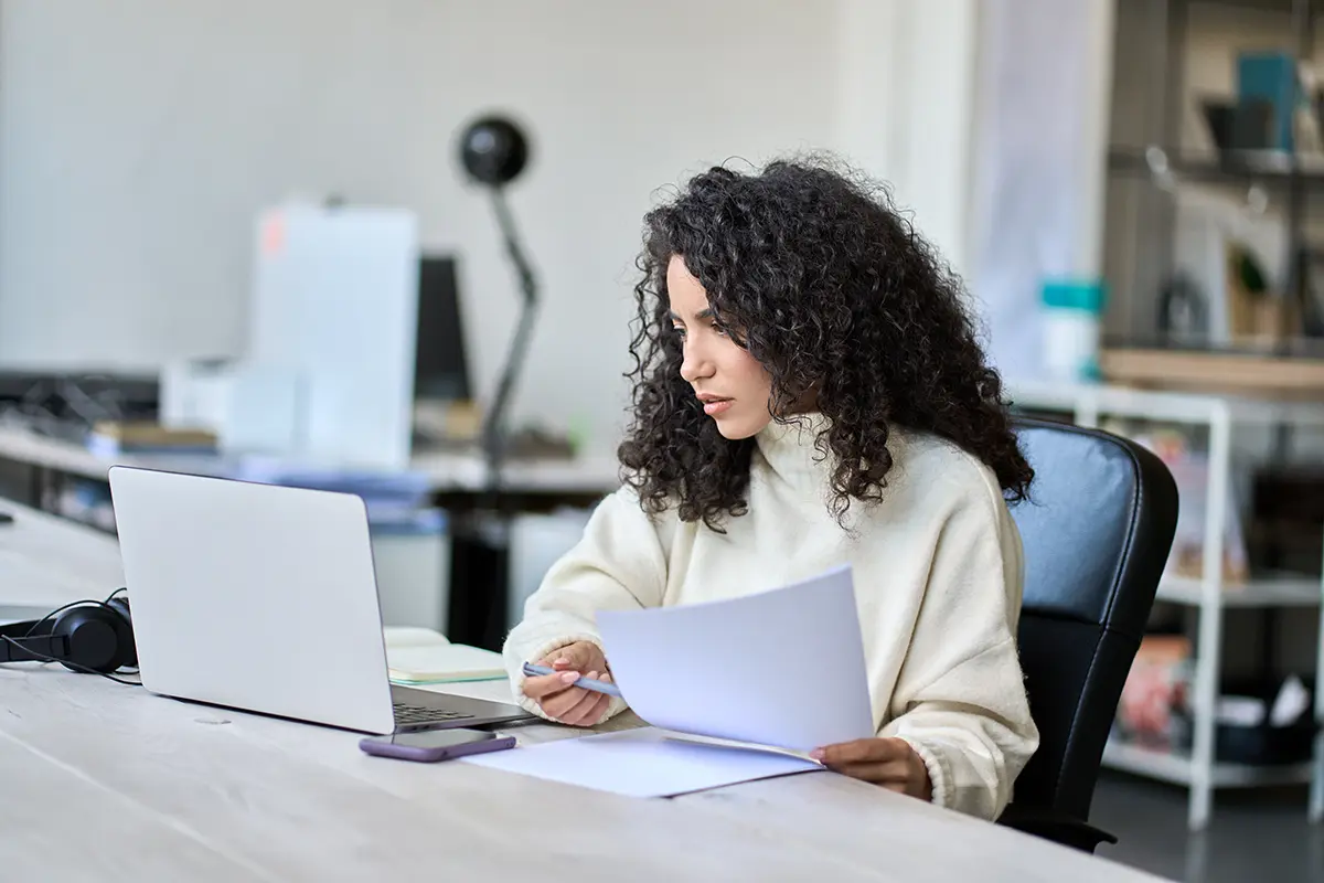 Young latin business woman accounting checking bills, working in office using laptop